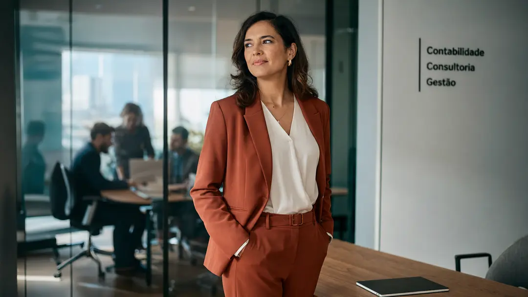 Líder feminina observando equipe através de vidro, promovendo retenção de talentos e alta performance contábil.